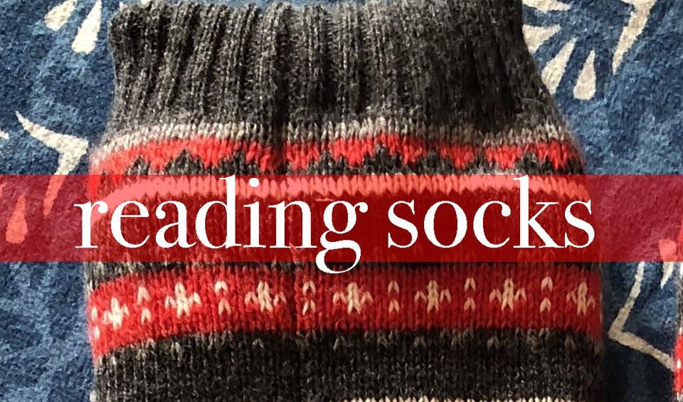 Warm wool socks with a vibrant red and gray pattern on a blue background, perfect for cozy reading sessions; embrace your talent in work-life balance.