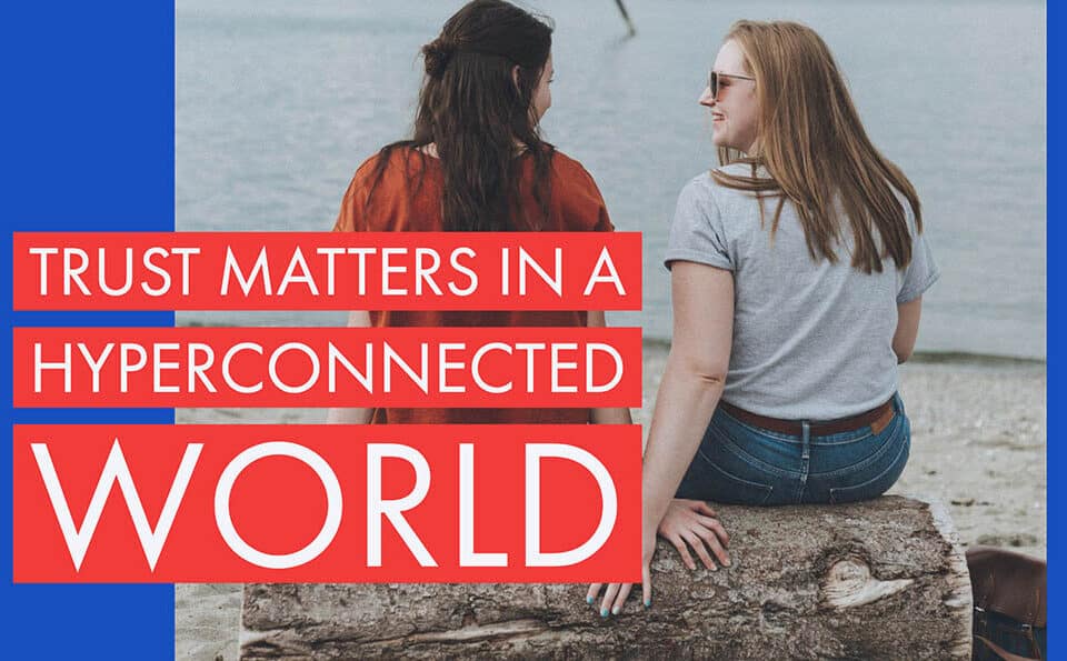 Two women chat by the water, highlighting trust in a hyperconnected world. Perfect blend of career, leadership, and HR insights for the aspiring author.